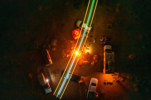 Zdjęcie zdjęcie lotnicze ognia obozowego, gdy przyjaciele kempują na lądzie z samolotem rc oświetlającym niebo