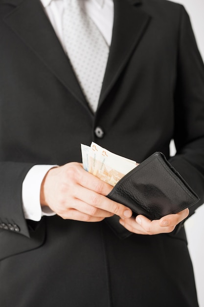zdjęcie mężczyzny z rękami z torebką liczącą gotówkę w euro