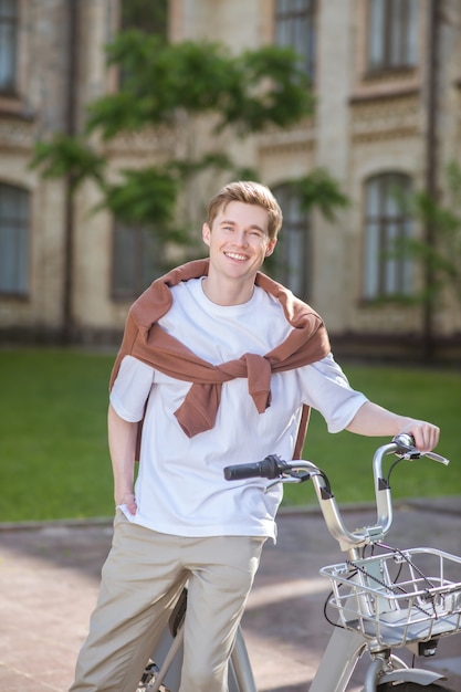 Zdjęcie młodego chłopaka stojącego obok roweru