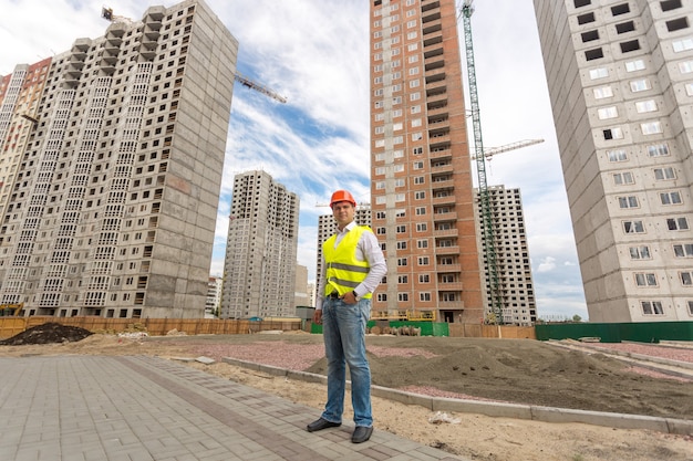 Zdjęcie Młodego Inżyniera Budowlanego Stojącego Przed Budynkami W Budowie