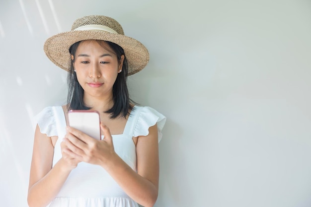 Zdjęcie młodej kobiety szczęśliwej w białej sukni i słomkowym kapeluszu pozytywny uśmiech użyj smartfona Koncepcja technologii społecznej podróży odpoczynku