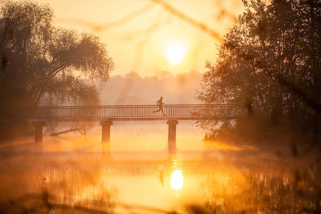 Zdjęcie o zachodzie słońca mężczyzny biegnącego przez most?