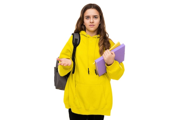 Zdjęcie pięknego zadawania pytań i zadawania pytań brunetki nastolatka w stylowej żółtej sportowej bluzie z kapturem