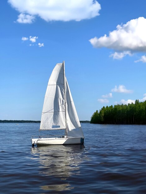 Zdjęcie pięknej białej żaglowej łodzi, małego jachtu z żaglem w letni dzień na rzece Wołga