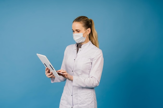 Zdjęcie pięknej pani doktor nosi maskę ochronną biały fartuch laboratoryjny na białym tle w kolorze niebieskim