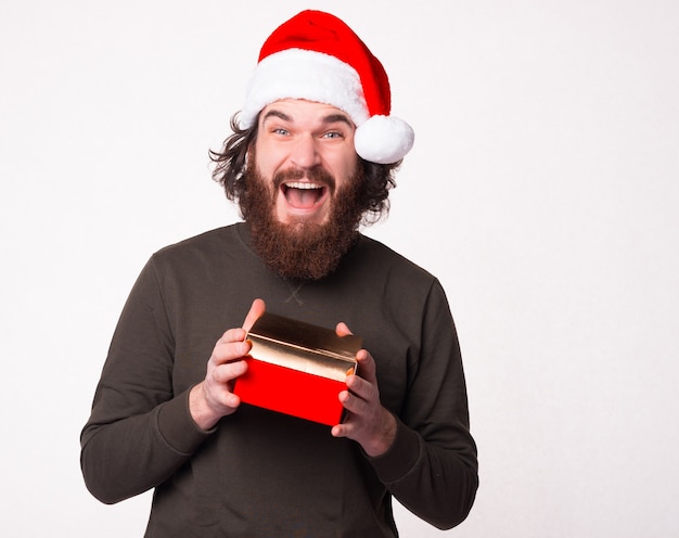 Zdjęcie podekscytowanego mężczyzny właśnie otrzymało prezent świąteczny w czapce Świętego Mikołaja