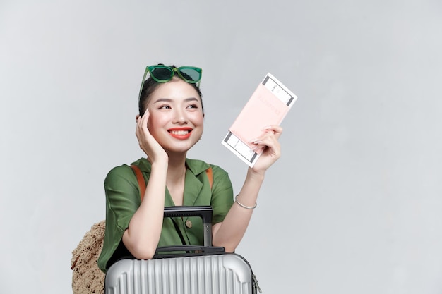 Zdjęcie podekscytowanej młodej ładnej turystki z walizką trzymającą paszport z biletami