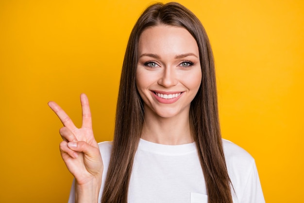 Zdjęcie portret uśmiechniętej kobiety pokazującej znak v na żywym żółtym kolorowym tle