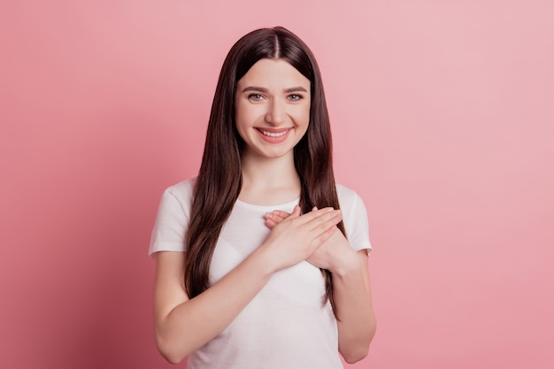 Zdjęcie Portret Wdzięcznej Uśmiechniętej Dziewczyny Z Wdzięcznością Trzymającą Ręce Na Klatce Piersiowej Izolowane Na Pastelowym Różowym Kolorze Tła