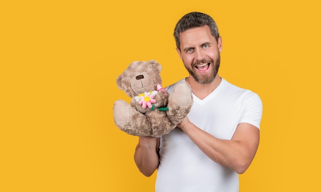 Zdjęcie pozytywnego faceta trzymającego valentine zabawki niedźwiedzia Facet trzyma valentine zabawki niedźwiedzia odizolowane na żółto