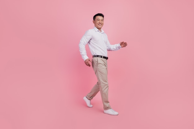 Zdjęcie Profilowe Całego Ciała Młodego Wesołego Azjatyckiego Mężczyzny Idzie Na Spacer W Pośpiechu Na Randkę Na Białym Tle Na Różowym Tle