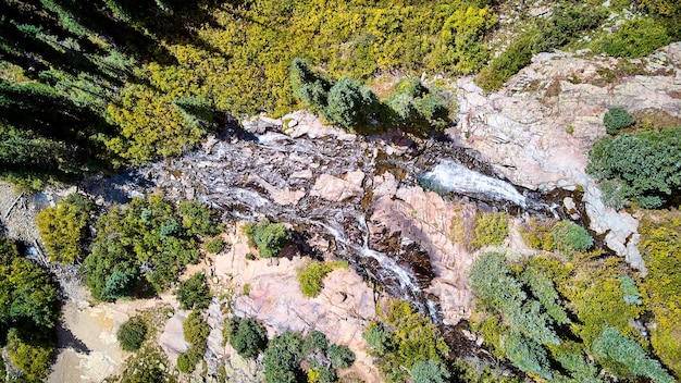 Zdjęcie przedstawiające widok z lotu ptaka na bliźniacze wodospady w skałach z rozsianymi drzewami