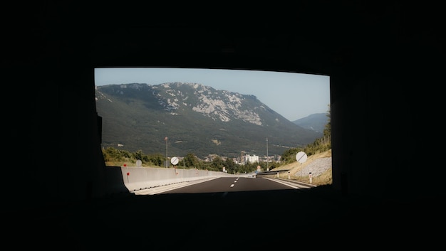 Zdjęcie przejazdu przez ciemny tunel na górskiej autostradzie z widokiem na światło na końcu tunelu