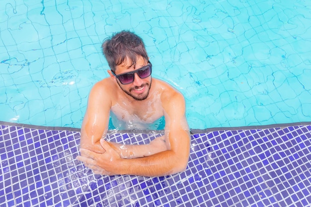 Zdjęcie przystojnego mężczyzny uśmiechającego się do basenu w letniej scenerii