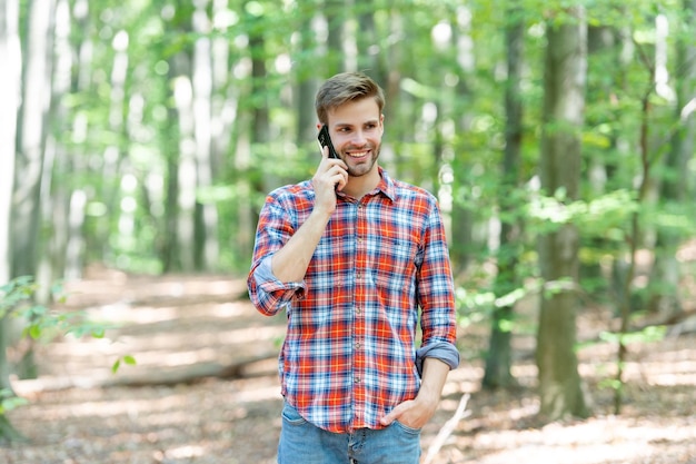 Zdjęcie radosnego mężczyzny ma rozmowę telefoniczną w lesie Mężczyzna ma rozmowę telefoniczną na zewnątrz