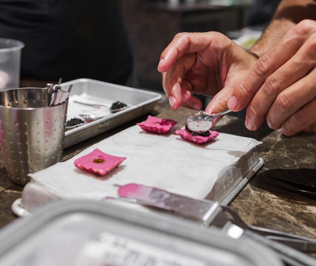 Zdjęcie rąk szefa kuchni przygotowujących potrawy dla smakoszy w różowych kolorach