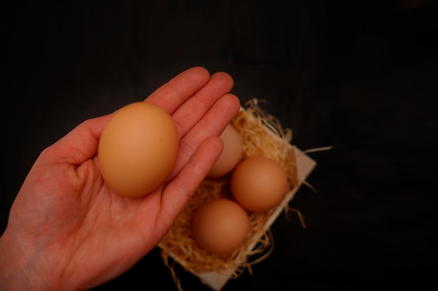 Zdjęcie zdjęcie ręki trzymającej organiczne jajko na ciemnym tle