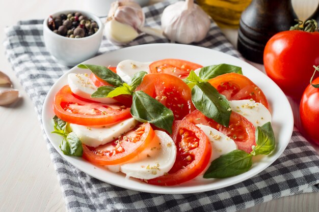 Zdjęcie zdjęcie sałatki caprese z pomidorami, bazylią, mozzarellą, oliwkami i oliwą z oliwek. włoskie tradycyjne składniki sałatki caprese. koncepcja śródziemnomorskiej, ekologicznej i naturalnej żywności.