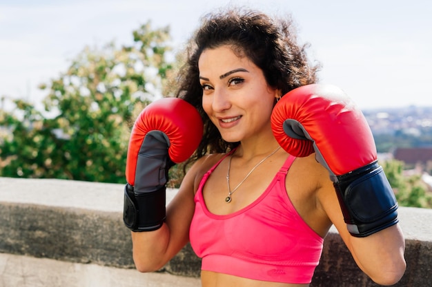 Zdjęcie silnej bokserki fitness w rękawiczkach, pozującej na zewnątrz