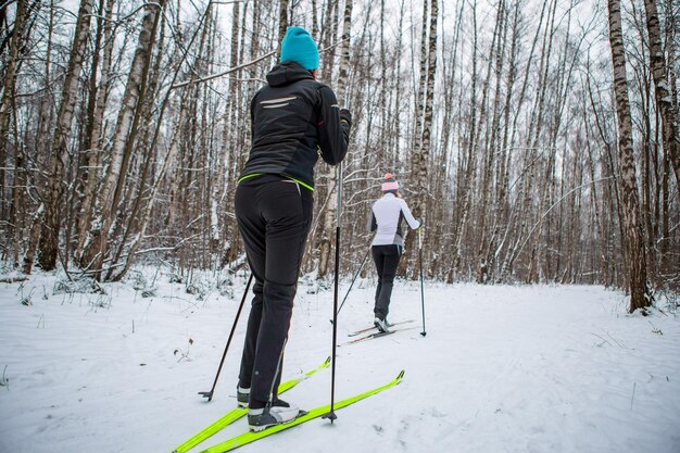 Zdjęcie sportowe dwie kobiety na nartach w zimowym lesie