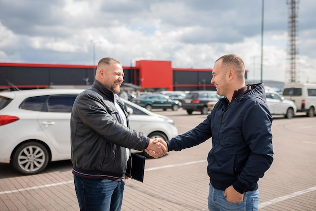 Zdjęcie zdjęcie sprzedawcy samochodu rozmawiającego z klientem o modelu samochoduxosoby ściskające sobie ręcexudana transakcja zakupu samochodu