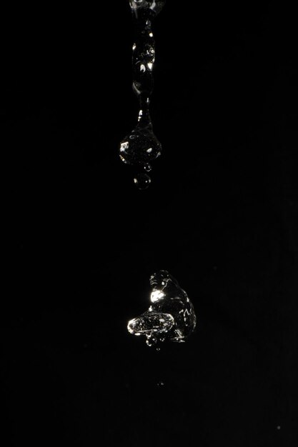 Zdjęcie zdjęcie studyjne wylewania wody z odbiciem światła na czarnym tle