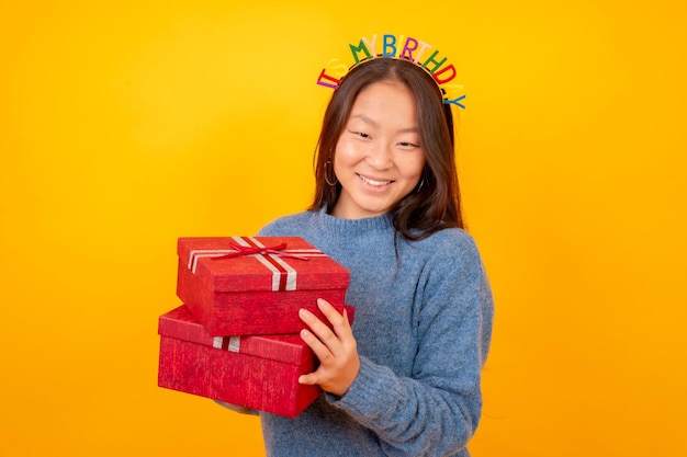 Zdjęcie studyjne z żółtym tłem chińskiej kobiety otrzymującej prezenty na urodziny