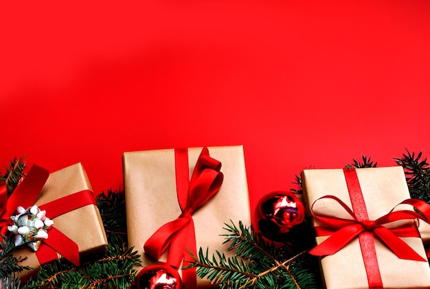 Zdjęcie świąteczne tło ozdobione świątecznymi prezentami i gałęziami jodły na czerwonym tle