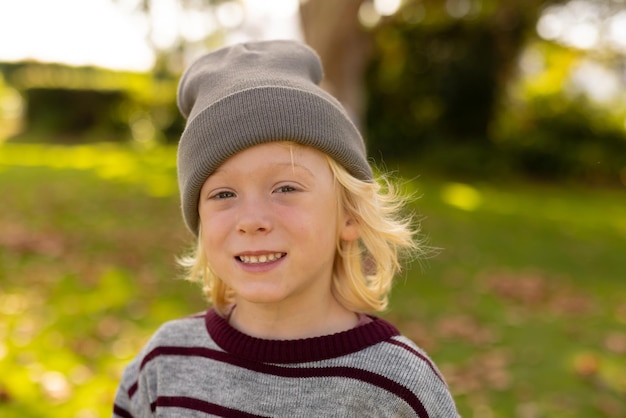 Zdjęcie szczęśliwego białego chłopca uśmiechającego się do kamery w ogrodzie