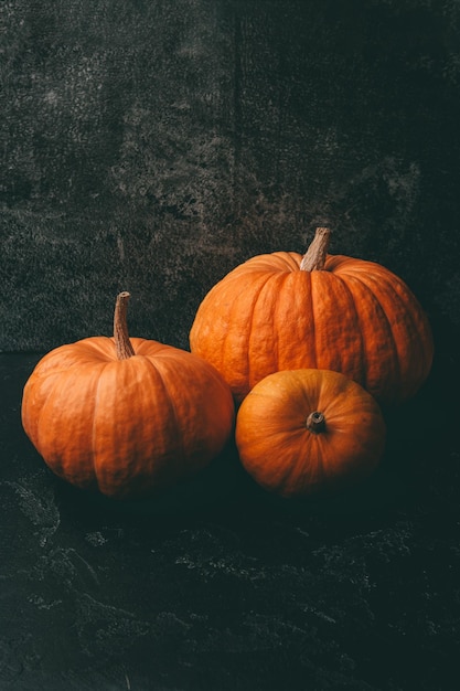 Zdjęcie trzech pomarańczowych dyń na czarnym tle obchody halloween