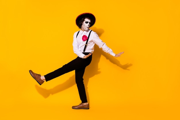 Zdjęcie upiorny duch facet taniec hiszpański taniec latynoski beztroski festiwal ręce zamknięte oczy nosić biała koszula śmierć kostium cukier czaszka szelki spodnie buty na białym tle żółty kolor tło