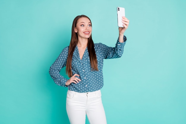 Zdjęcie Uroczej, Dobrze Wyglądającej Dziewczyny Robi Selfie Na Telefonie Komórkowym Na Białym Tle Nad Turkusowym Kolorem Tła