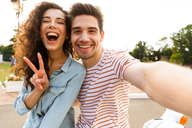 Zdjęcie Uśmiechniętej Pary Przy Selfie Na Telefon Komórkowy, Siedząc Razem Na Motocyklu W Parku Miejskim