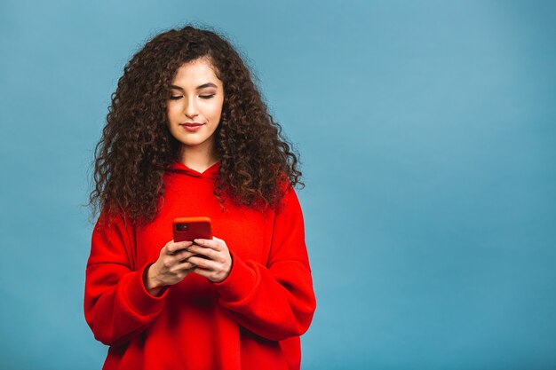 Zdjęcie Wesoły ładny Piękna Młoda Kobieta Na Czacie Przez Telefon Komórkowy Na Białym Tle Na Tle Niebieskiej ściany. Korzystanie Z Telefonu.