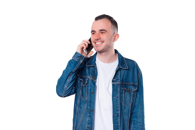 Zdjęcie wesoły młody przystojny mężczyzna rozmawia na smartfonie w niebieskiej kurtce dżinsowej