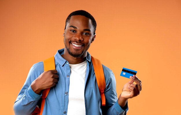 zdjęcie widok z przodu młody mężczyzna przygotowuje się do pieszych wędrówek trzymając kartę bankową na pomarańczowym tle