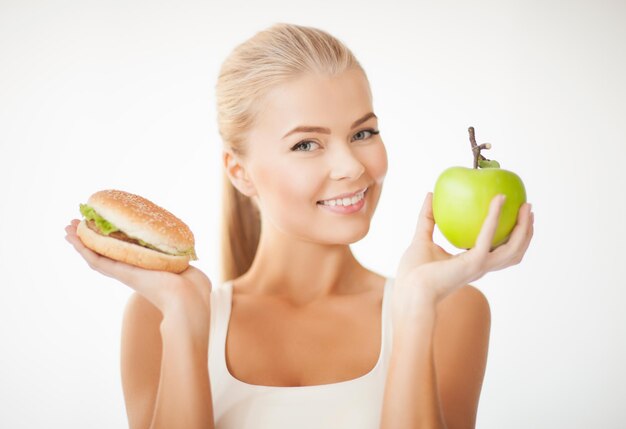 zdjęcie wysportowanej kobiety z jabłkiem i hamburgerem
