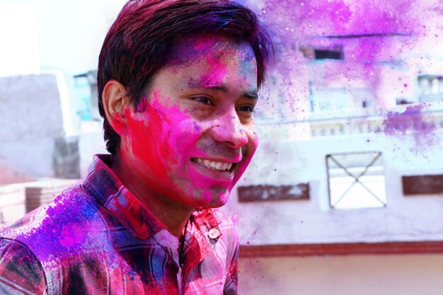 Zdjęcie zdjęcie z bliska indyjskiego młodego mężczyzny pokrytego wielobarwną suchą farbą na festiwalu holi
