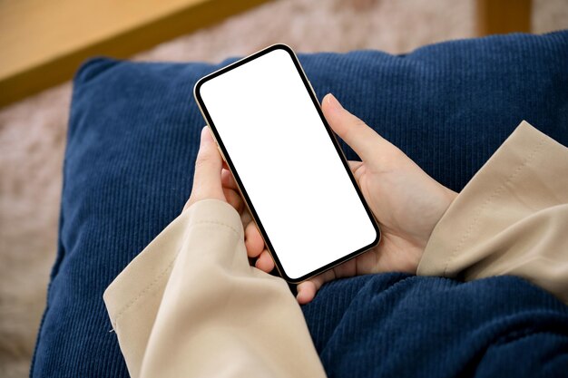 Zdjęcie z bliska Zrelaksowana kobieta siedzi na wygodnej sofie i korzysta z białego ekranu smartfona