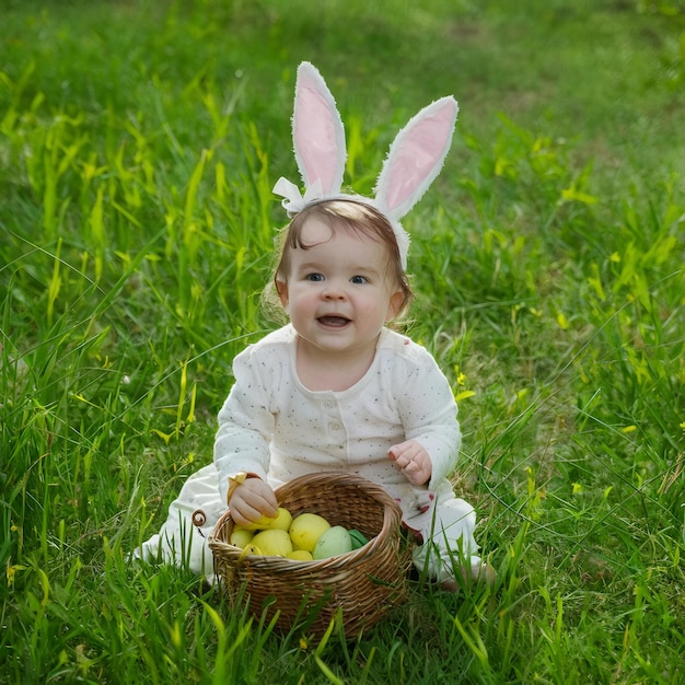 Zdjęcie z Dnia Wielkanocnego dziecka noszącego uszy króliki i koszyk z jajkami