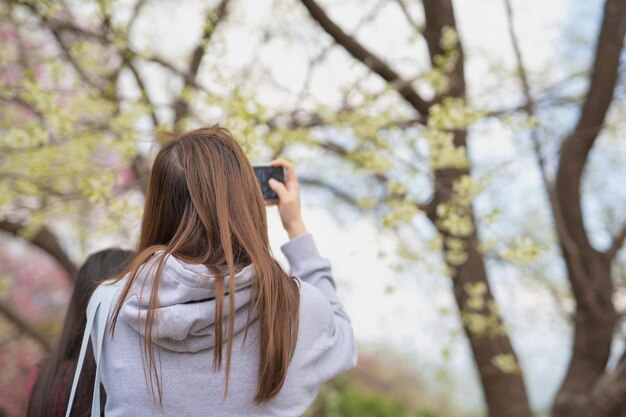 Zdjęcie zdjęcie z tyłu kobiety fotografującej za pomocą smartfona