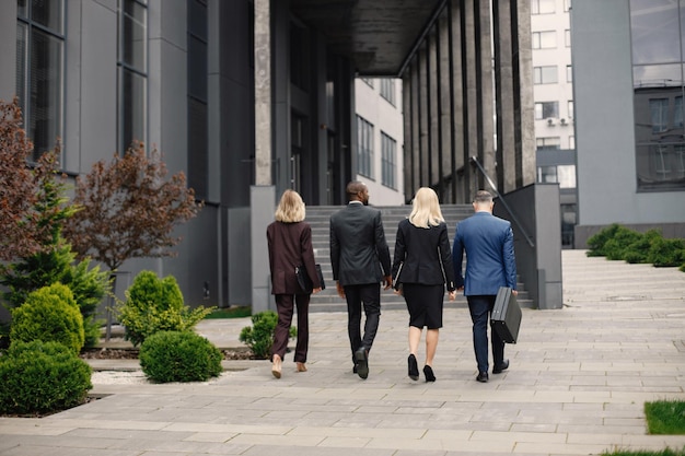 Zdjęcie z tyłu przedstawiające ludzi biznesu idących w kierunku nowoczesnego biura