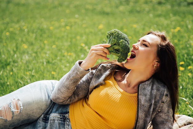 Zdrowa dieta. Piękna kobieta je świeże Organicznie brokuły. Zdrowa żywność, wegetariańskie odżywianie i koncepcja zdrowia