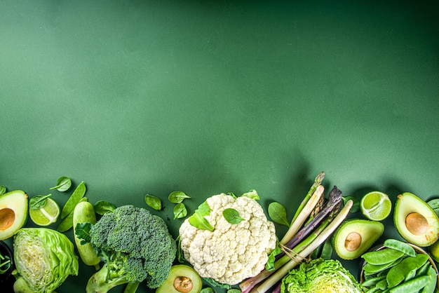 Zdjęcie zdrowa dieta wiosna żywności tło. asortyment świeżych surowych ekologicznych zielonych warzyw - brokuły, kalafior, cukinia, ogórki, szparagi, szpinak, awokado, kapusta na ciemnozielonym tle