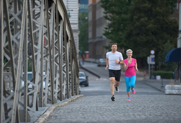 zdrowa dojrzała para jogging w mieście wczesnym rankiem ze wschodem słońca w tle