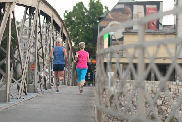 zdrowa dojrzała para jogging w mieście wczesnym rankiem ze wschodem słońca w tle