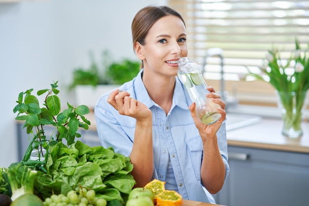 zdrowa dorosła kobieta z zielonym jedzeniem w kuchni