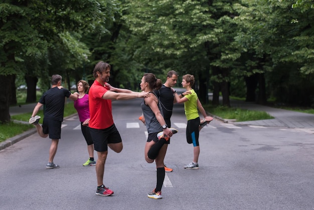 zdrowa drużyna biegaczy rozgrzewająca się i rozciągająca się w miejskim parku przed treningiem porannym