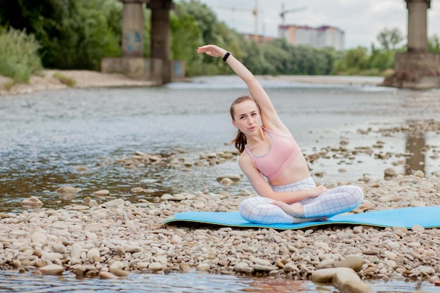 Zdrowa dziewczyna relaksujący podczas medytacji i ćwiczeń jogi w pięknej przyrody na brzegu rzeki