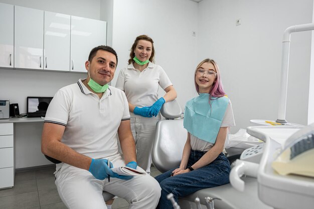 Zdrowa kobieta uśmiecha się szczęśliwie w gabinecie dentystycznym obok dentysty